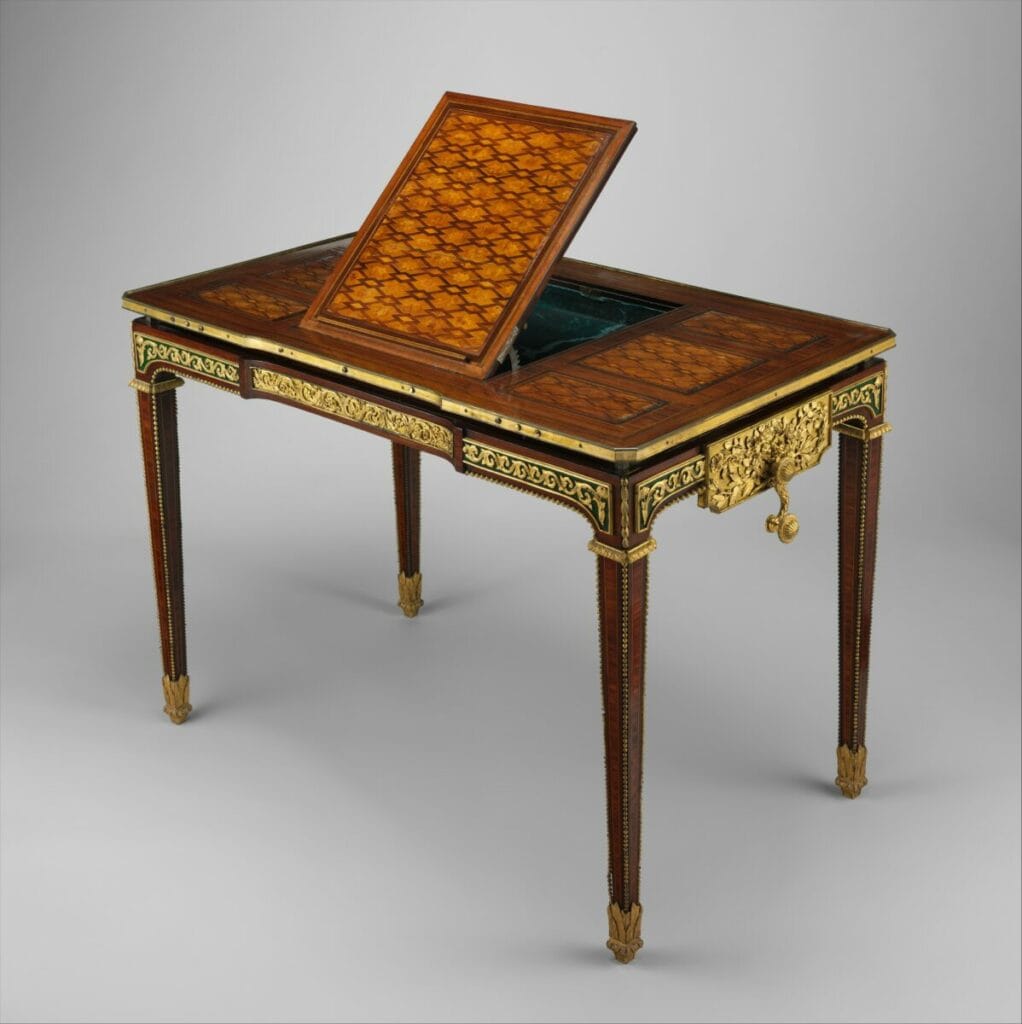 Gros plan sur la marqueterie raffinée d'une table de Riesener: treillis, rosette, essences variées et finesse de l'exécution