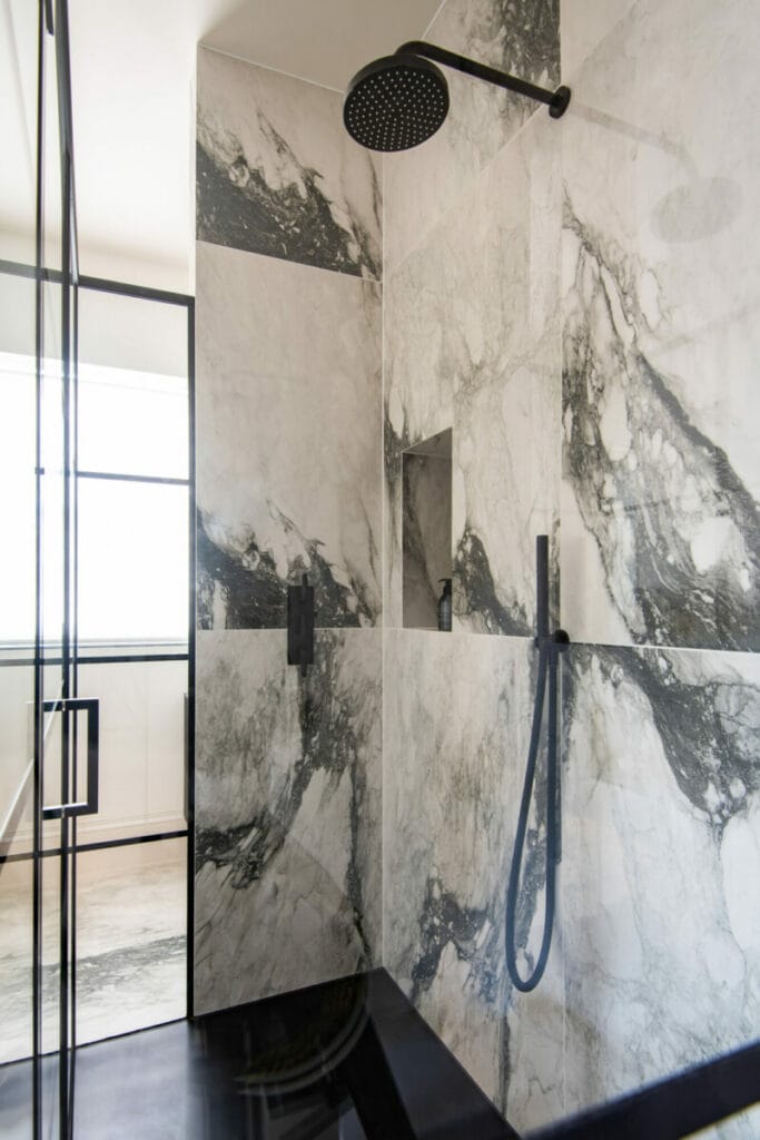 Douche contemporaine en marbre noir et blanc avec robinetterie noire mate, design Samuel Heath.