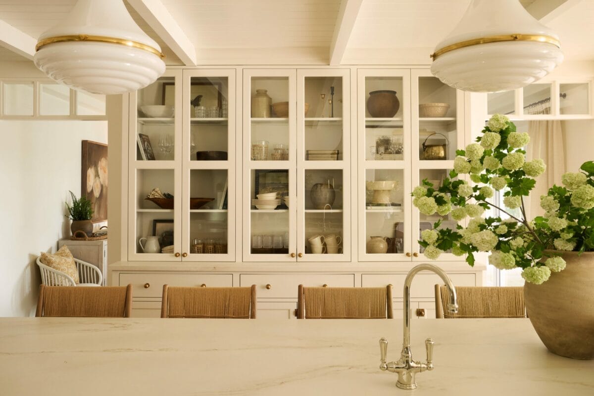 Cuisine lumineuse du projet Giroux par AKB Design, avec îlot en marbre clair, mobilier sur mesure crème et suspension vintage, reflétant une élégance intemporelle.