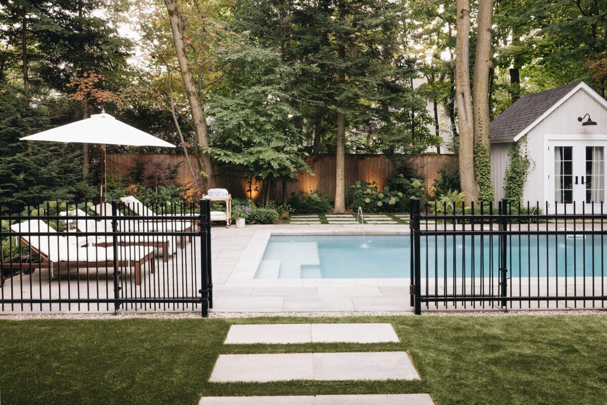 Piscine contemporaine du projet AKB Design, entourée de chaises longues et d’un pavillon en bois, intégrée dans un écrin de verdure pour une ambiance raffinée et naturelle.