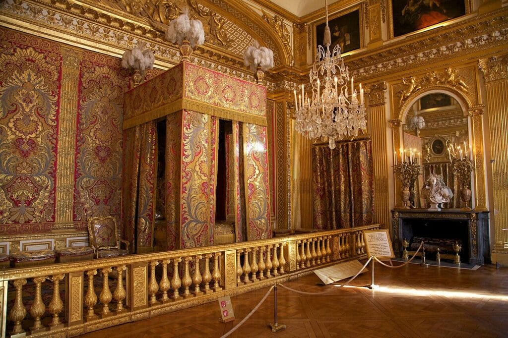 Chambre du Roi, château de Versailles XVIIᵉ siècle Lit d’apparat de Louis XIV, centre symbolique du pouvoir monarchique et du cérémonial royal. Lit du Roi à Versailles — Style Louis XIV Baldaquin monumental, textiles brodés et dorures, le lit comme trône domestique.