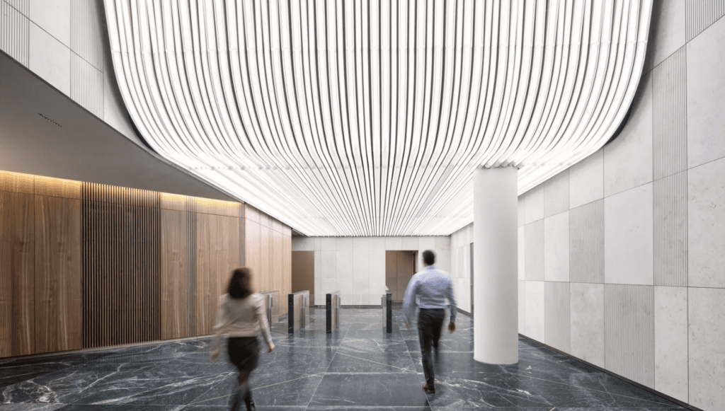 Hall du projet FOUR Frankfurt éclairé par un plafond lumineux sculptural de Zumtobel, lignes LED continues créant un volume ondulant au-dessus d’un espace contemporain en marbre et bois.