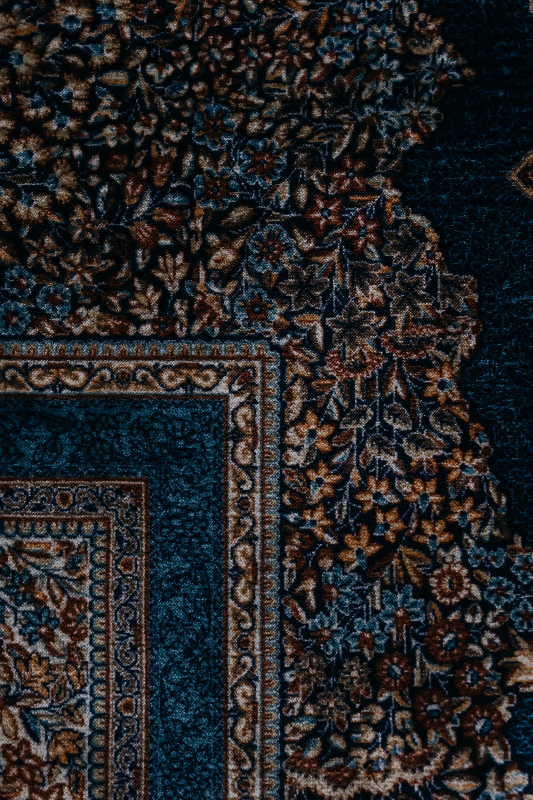 Elegant and detailed ornate carpet design captured from a top view angle, showcasing intricate patterns and rich textures.