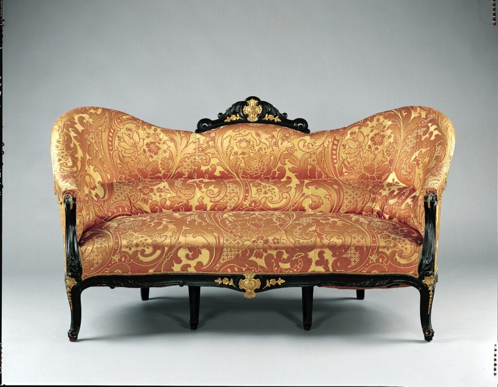 Canapé du milieu du XIXᵉ siècle, structure en bois sombre et garniture textile à motif, mobilier caractéristique du style Louis-Philippe.