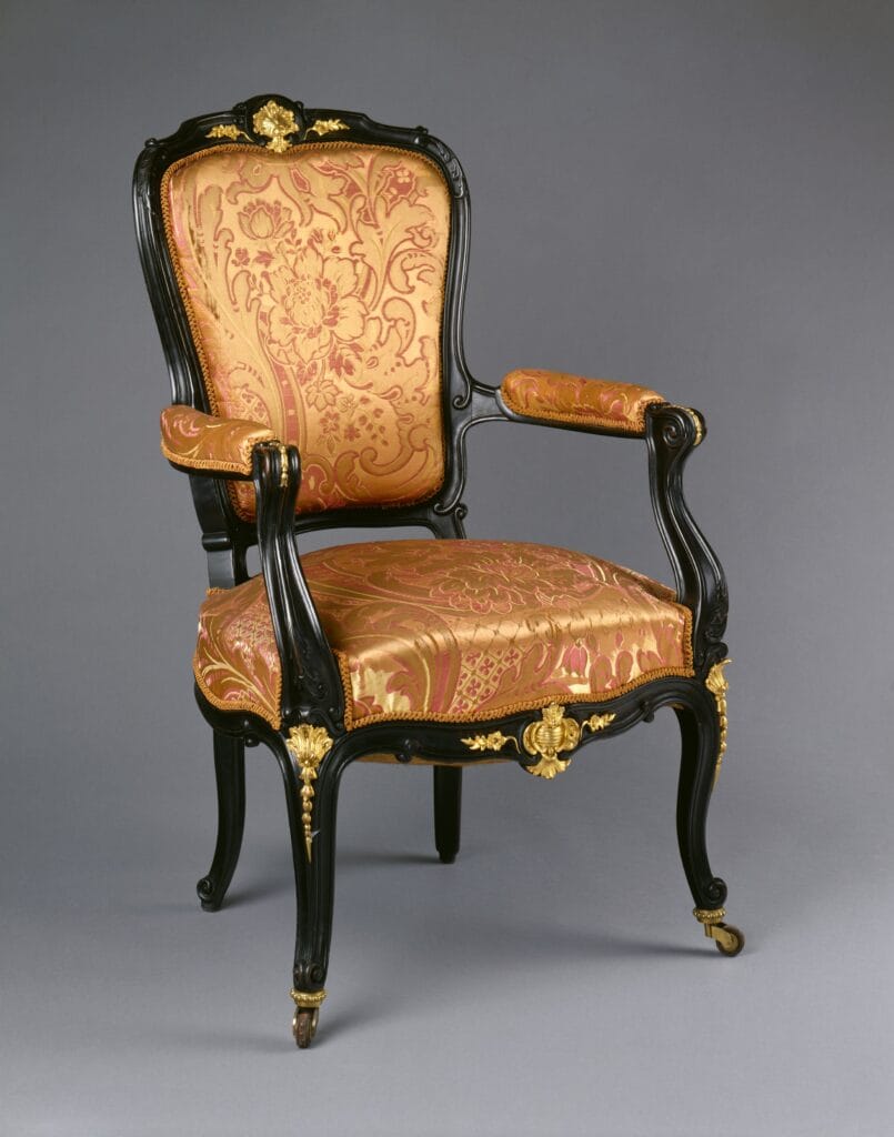 Fauteuil français du milieu du XIXᵉ siècle, structure en bois sombre, accotoirs galbés et garniture textile, caractéristique du style Louis-Philippe.