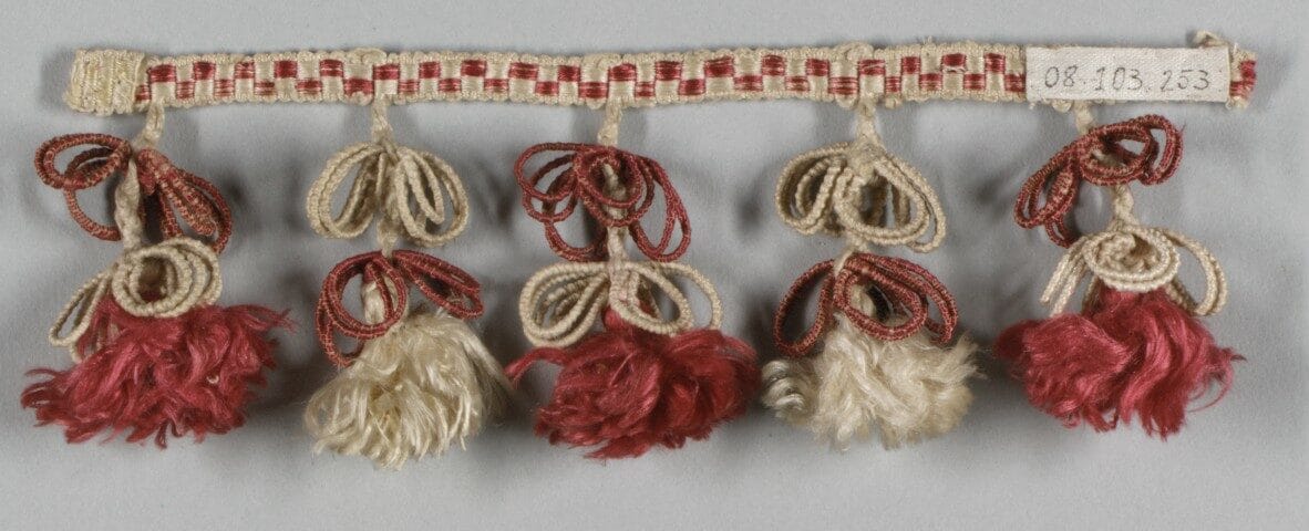 Nineteenth-century furnishing passementerie with fringes and tassels in red and ecru threads, characteristic of the Louis-Philippe period.