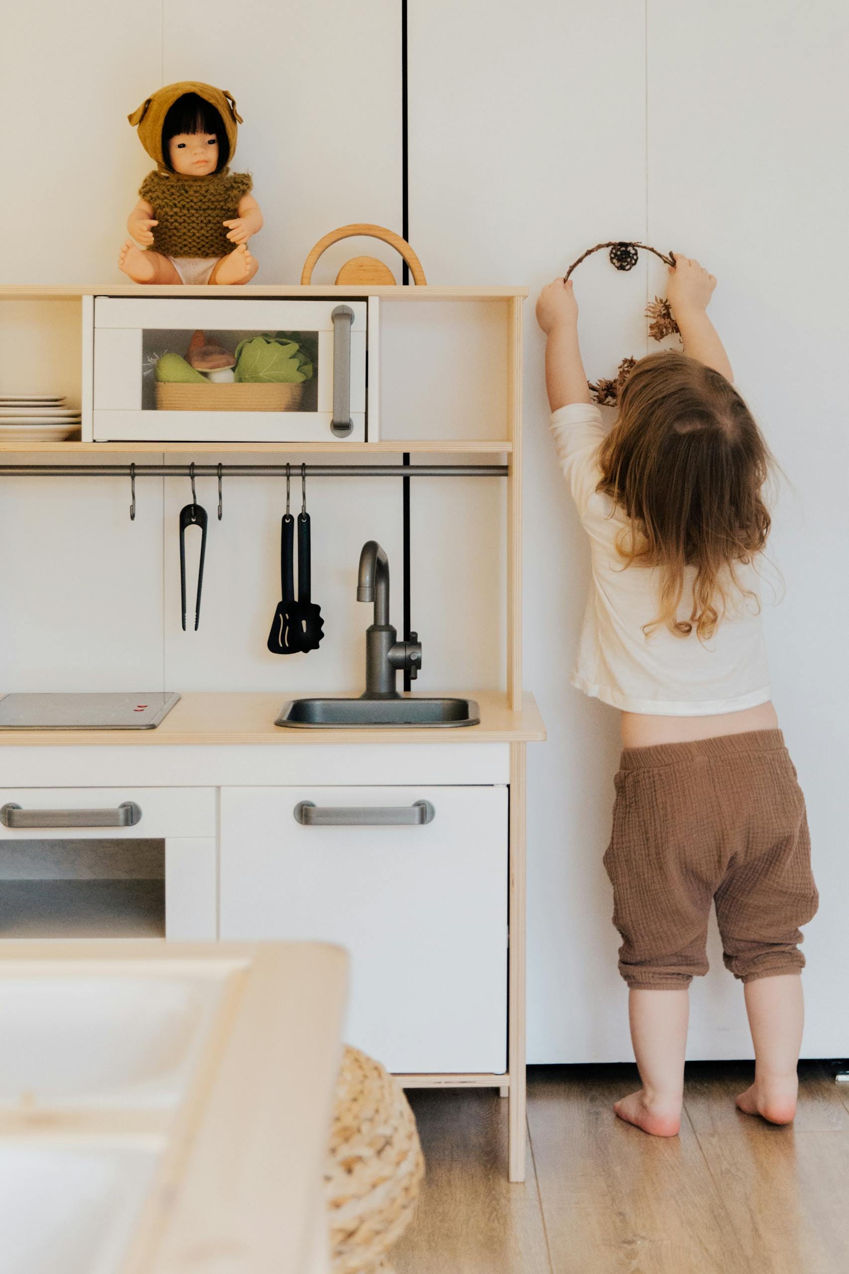 A child reaching up in a contemporary play kitchen, creating a fun and creative indoor scene.