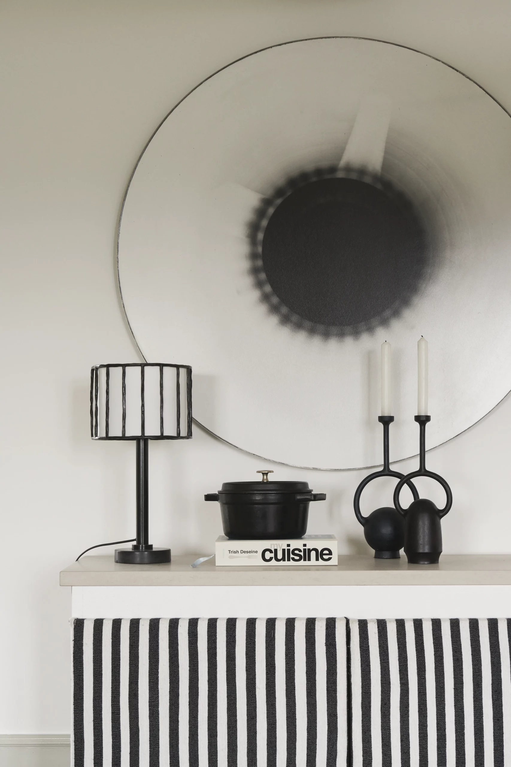 Minimalist kitchen detail: light worktop, black and white striped curtain, cast iron cocotte and graphic black objects